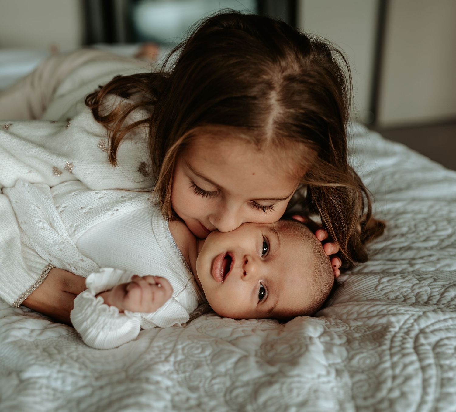Intimate lifestyle photos of gentle embraces on white bedding.