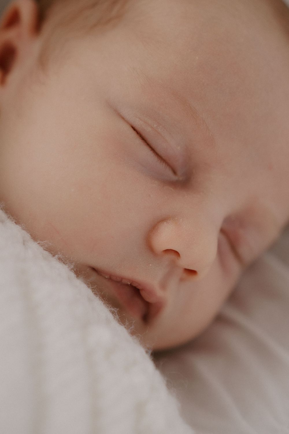 a close up photo of a newborn babys face cropped in at the ear