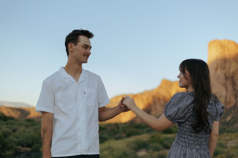 A couple shares a romantic moment at sunset against a backdrop of majestic desert cliffs.