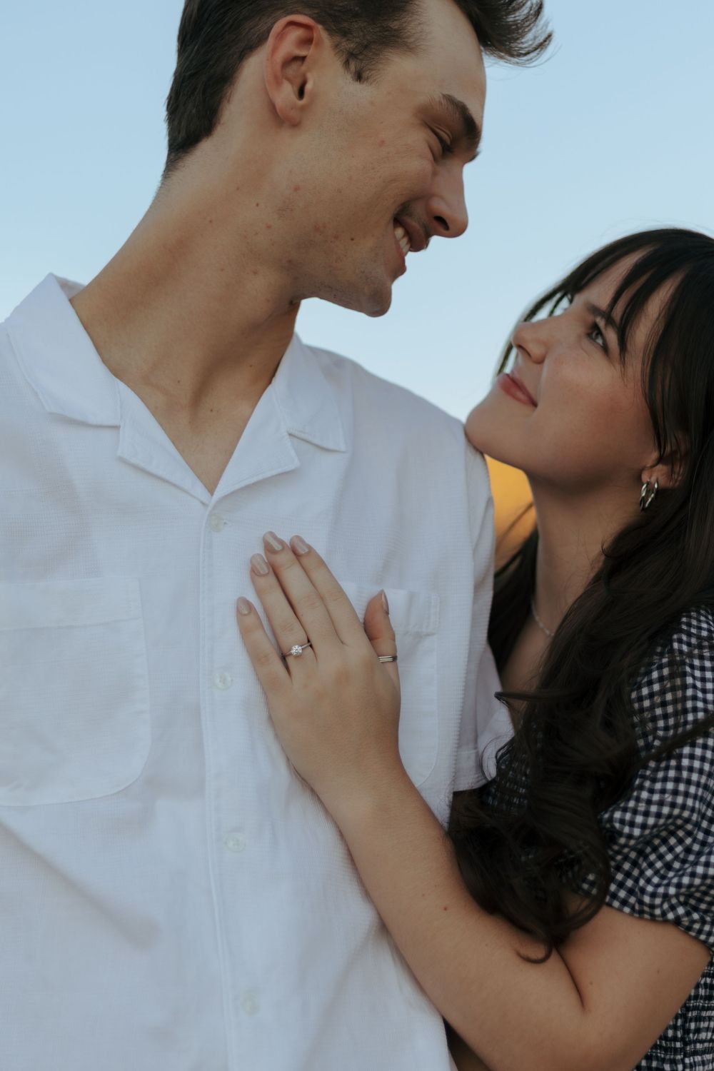 A romantic couple embraces outdoors with golden cliffs in the background.
