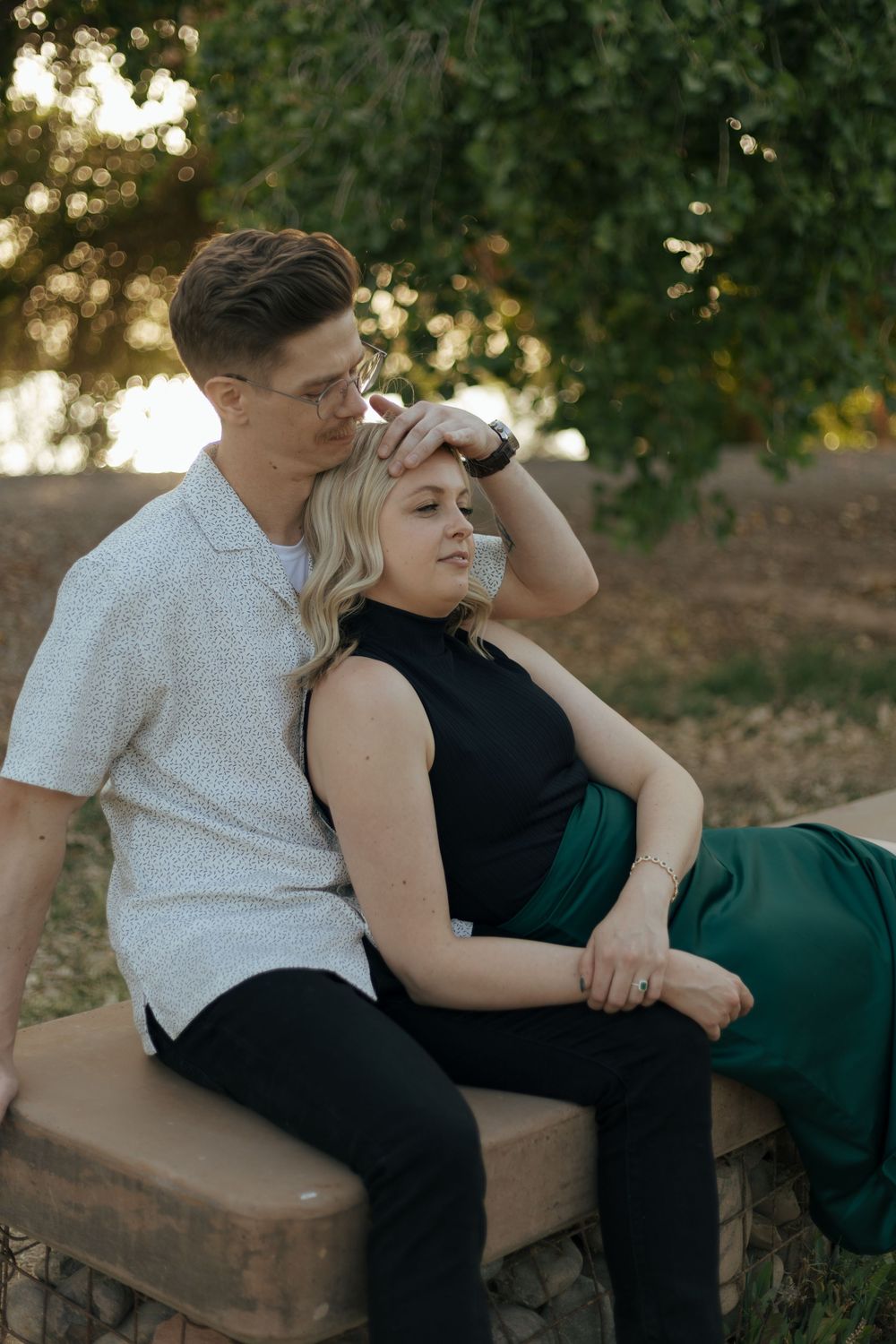 Couple relaxing together on outdoor bench surrounded by greenery.