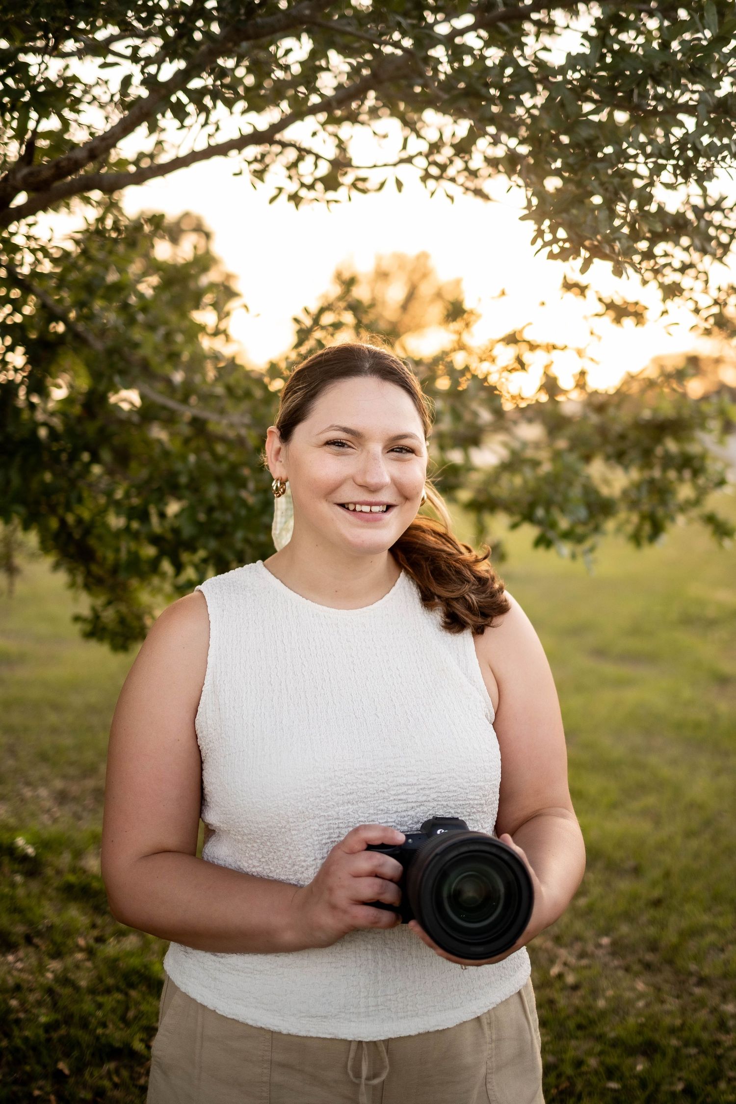 Lakeland Florida photographer Nichole holding camera outdoors during golden hour portrait session