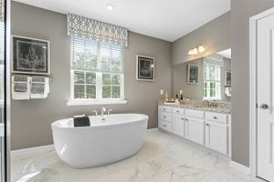 Luxurious master bathroom with freestanding tub, marble floors, and gray walls.