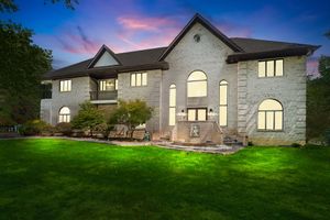 Stunning twilight exterior shots of modern stone mansion with illuminated windows.