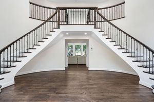 Grand foyer with curved staircase featuring dark wood railings and white trim details.