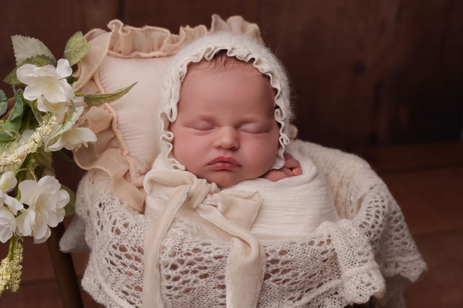 Sleeping baby in vintage white lace bonnet and wrap with floral accents.