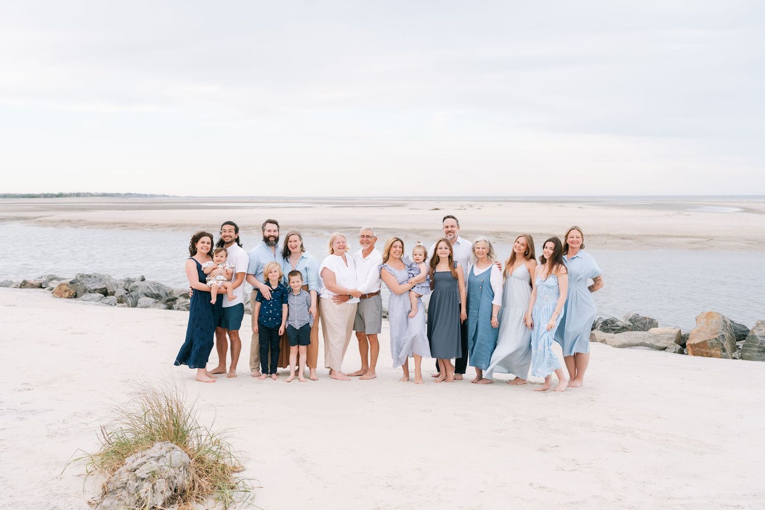 Extended family portrait on St. Simons Island beach with three generations smiling together during a sunset photography session.