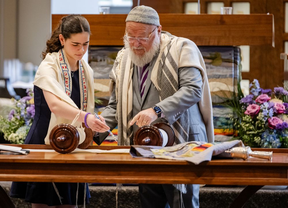 Rabbi and young woman in tallitot reading from Torah scrolls during a Bar or Bat Mitzvah ceremony.