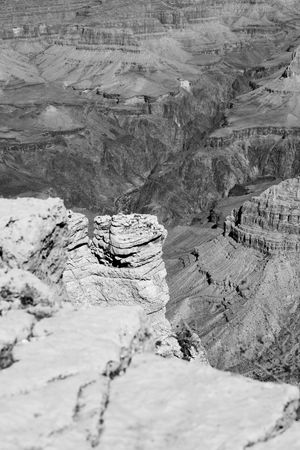 Black and white scenic view of rugged rock formations and layered cliffs at the Grand Canyon.