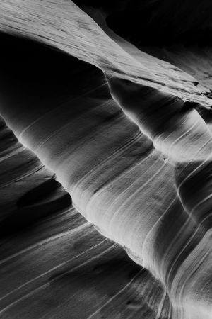 Black and white photograph of smooth, curved sandstone formations in Antelope Canyon showing dramatic light and shadows.