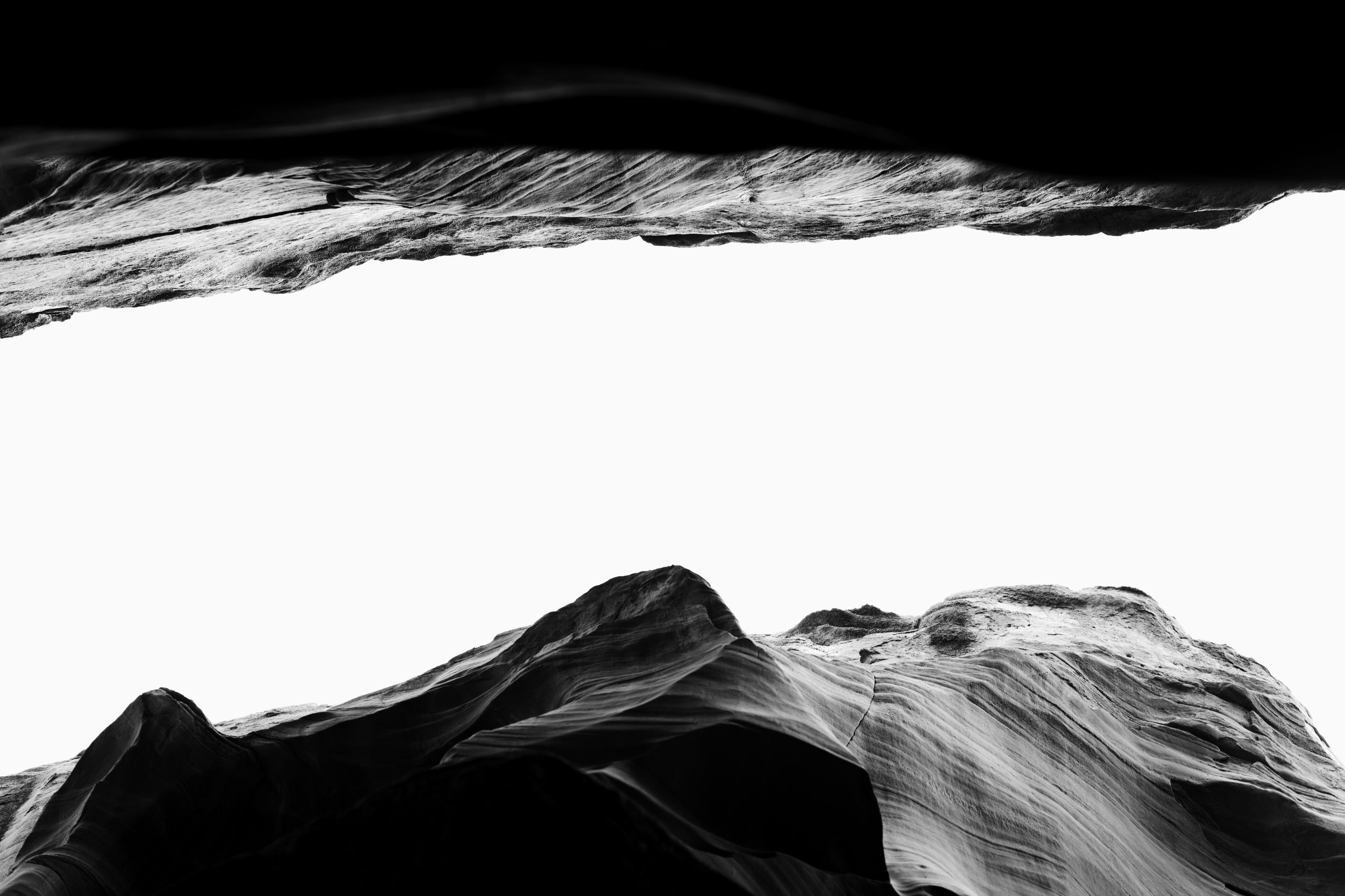Dramatic black and white aerial view of rugged mountain peaks with snow-capped ridges and deep valleys.
