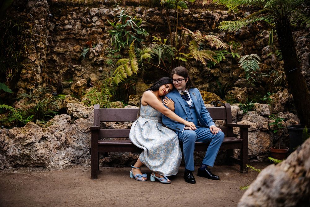 Engagement shoot captured by Lynette Matthews Photography -  a couple relax together on a bench in Botanic Gardens Southport