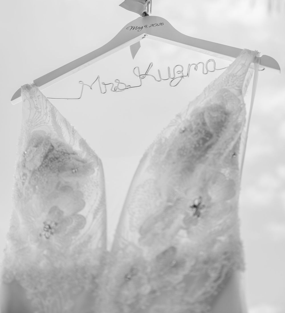 Black and white photo of lace wedding dress hanging on personalized Mrs. Kuzma wire hanger.