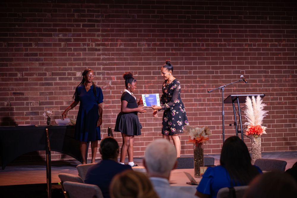 Performers on stage at a comedy club with exposed brick wall backdrop during a live show.