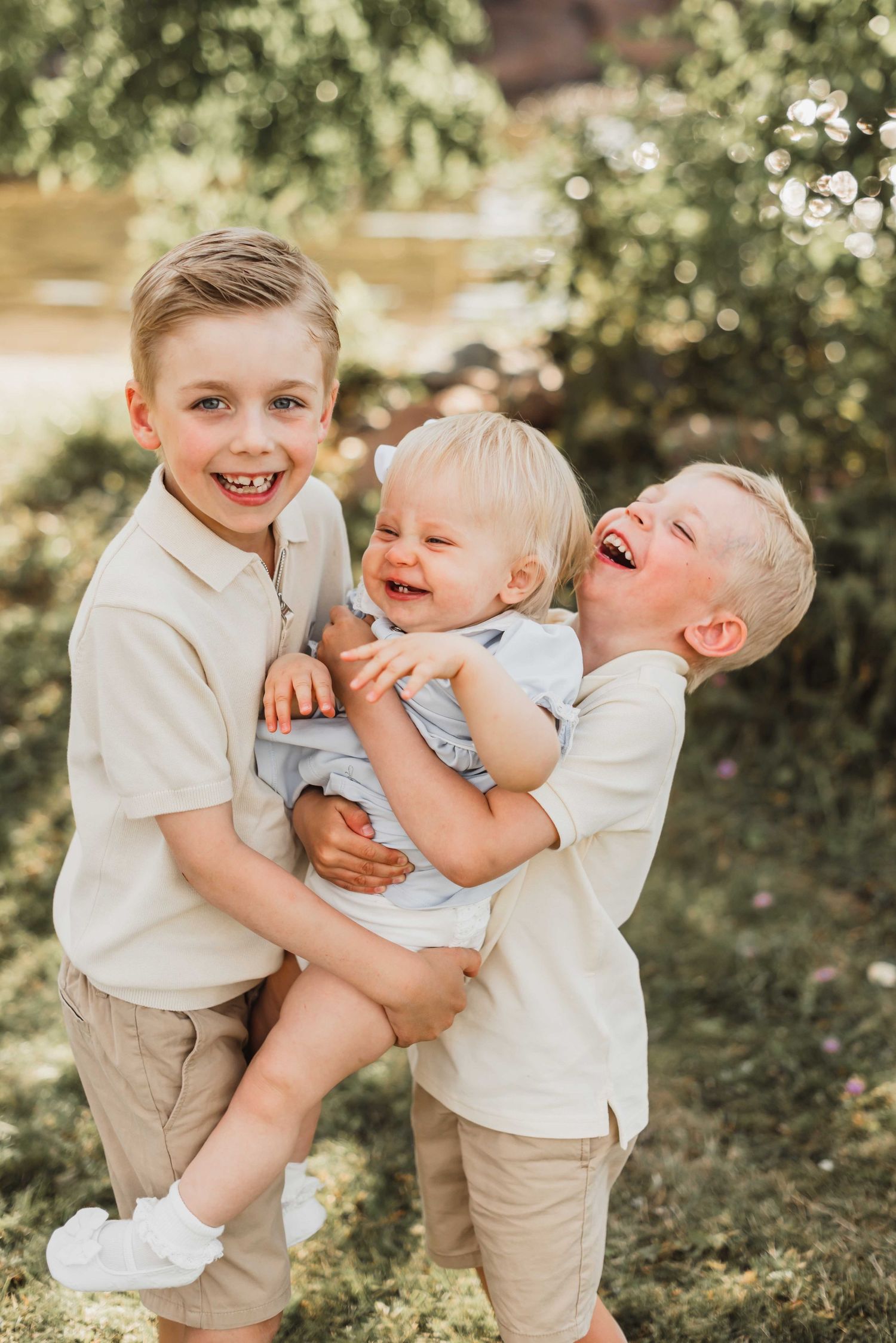 Family portrait of mother and children in white dresses sitting on blanket outdoors.