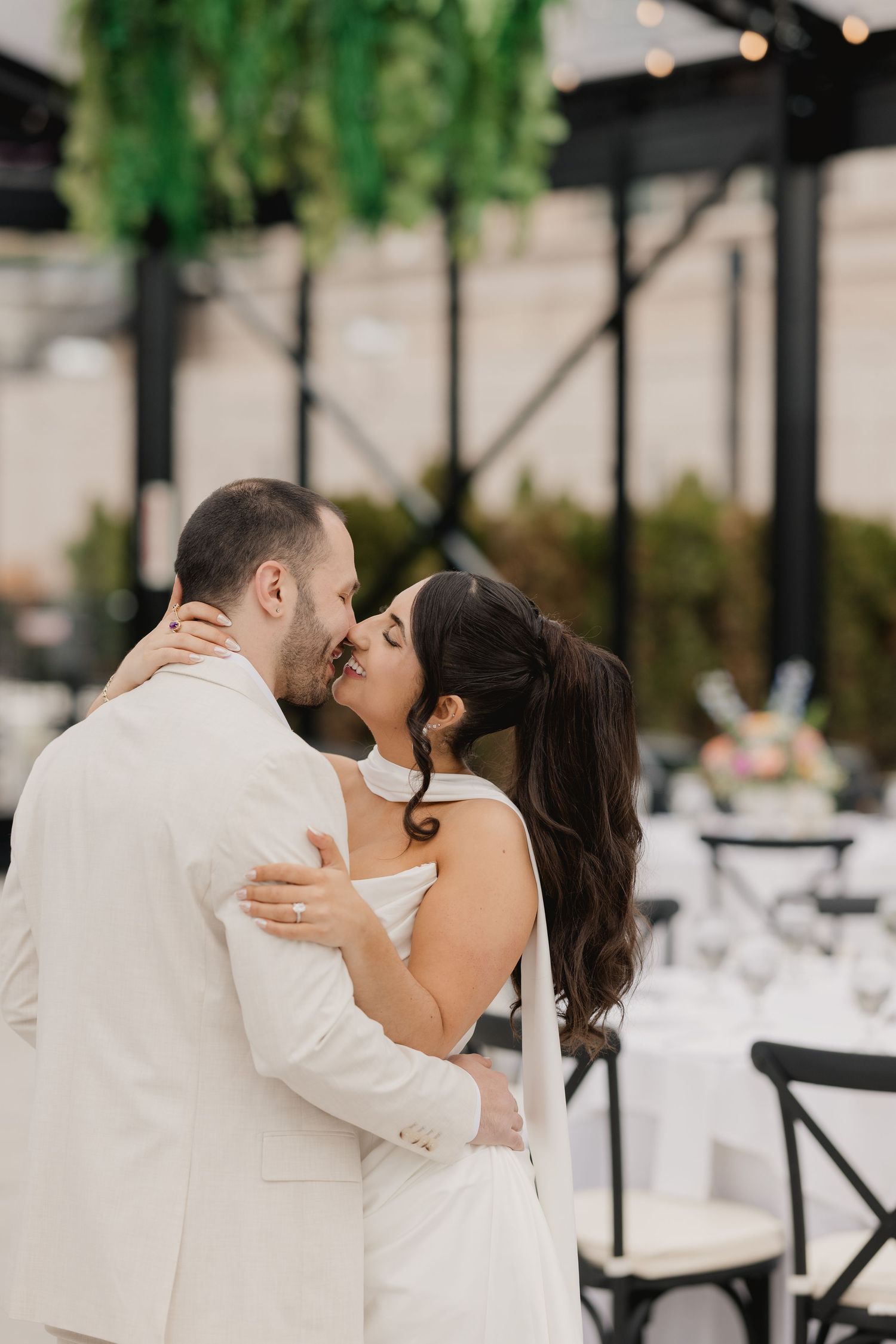 A bride and groom share a romantic first dance kiss at an elegant indoor wedding reception venue.