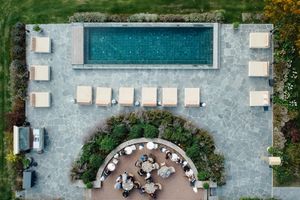 Aerial view of a luxurious swimming pool with white lounge chairs and tropical landscaping at a resort property.