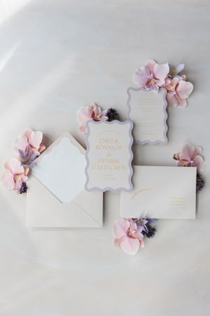 Elegant wedding invitations styled with soft pink floral accents on white background.