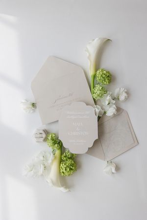 Wedding invitation cards with white calla lilies, green hydrangeas and small white flowers on light background.