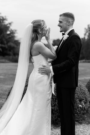 A joyful moment between newlyweds in formal attire sharing a laugh during their outdoor wedding photoshoot.