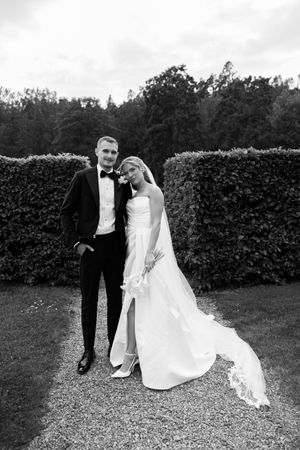 Black and white wedding photography progression showing a couple playfully bending down on garden path.