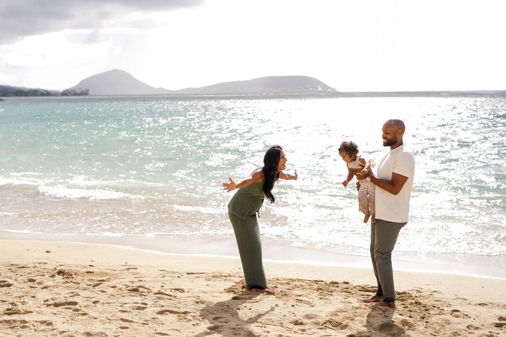 People enjoying a sunny day at a tropical beach with mountains and sparkling water in the background.