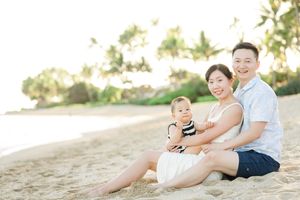 Family members sit together laughing and enjoying a sunny day at the beach.