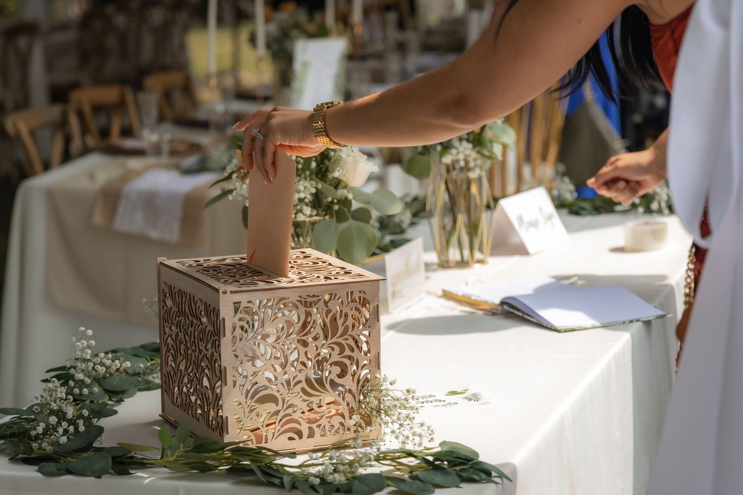 Hands placing rings in an ornate wooden box during a wedding ceremony.