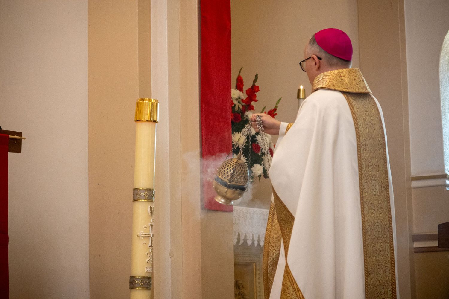 Cathedral altar area decorated with white and red liturgical cloths and candles in a traditional church setting.