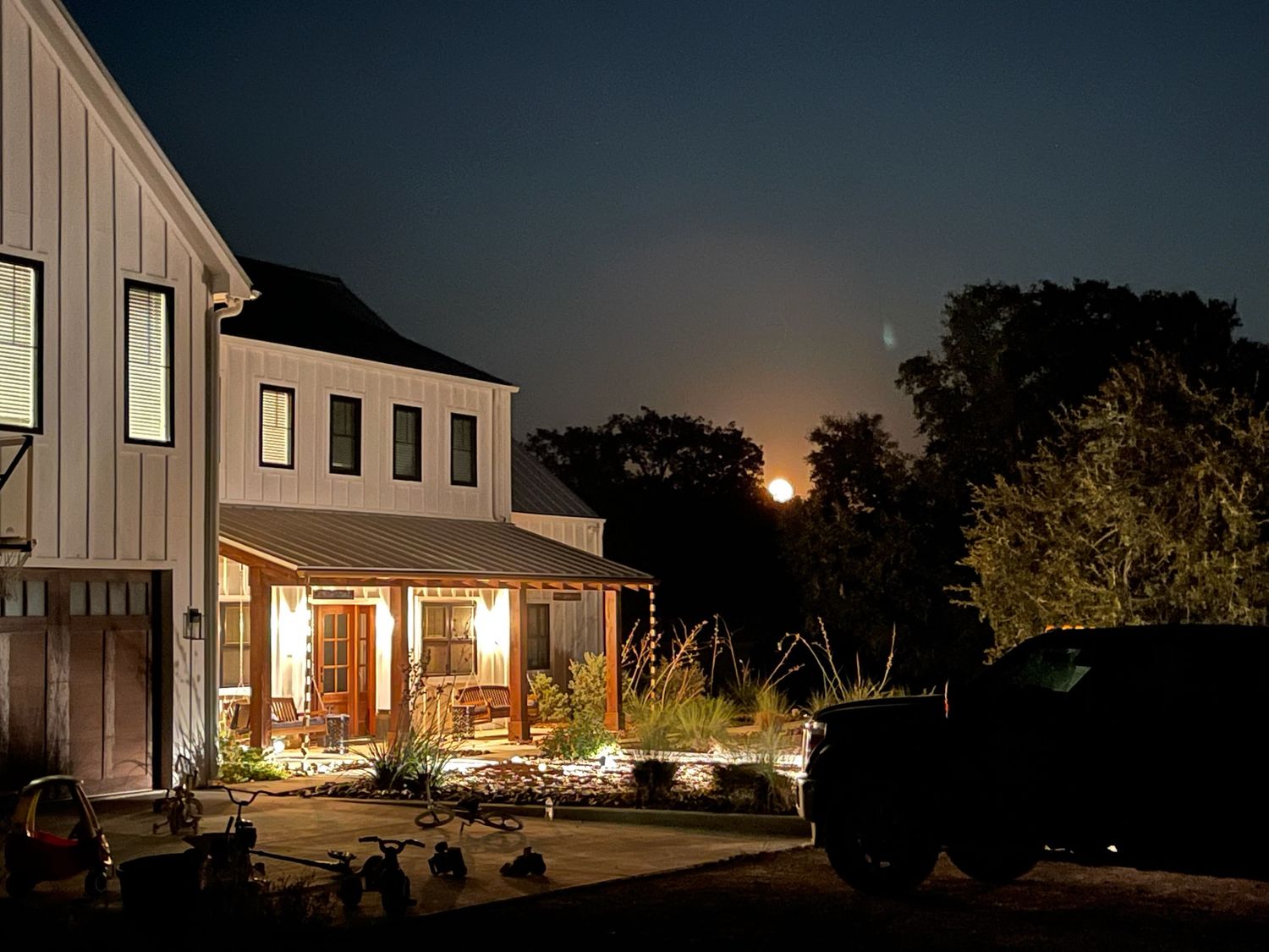 Night view of modern farmhouse exterior with warm lighting.