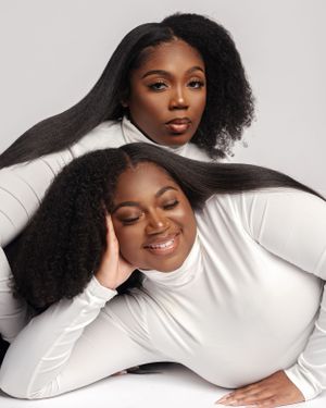Two models wearing white turtleneck tops pose elegantly together against a light background for product shot.
