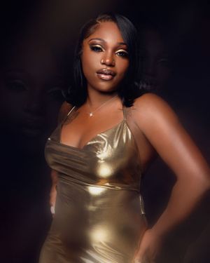 Portrait of a person wearing a shimmering gold dress against a dark background with soft lighting and glamorous makeup.
