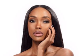 Beauty portrait of a woman with flawless glowing skin, mauve lips, long straight dark hair and natural makeup look.