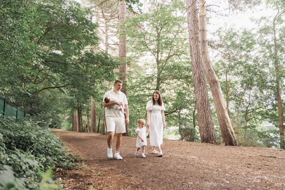 A family walking together on a wooded trail surrounded by tall trees.