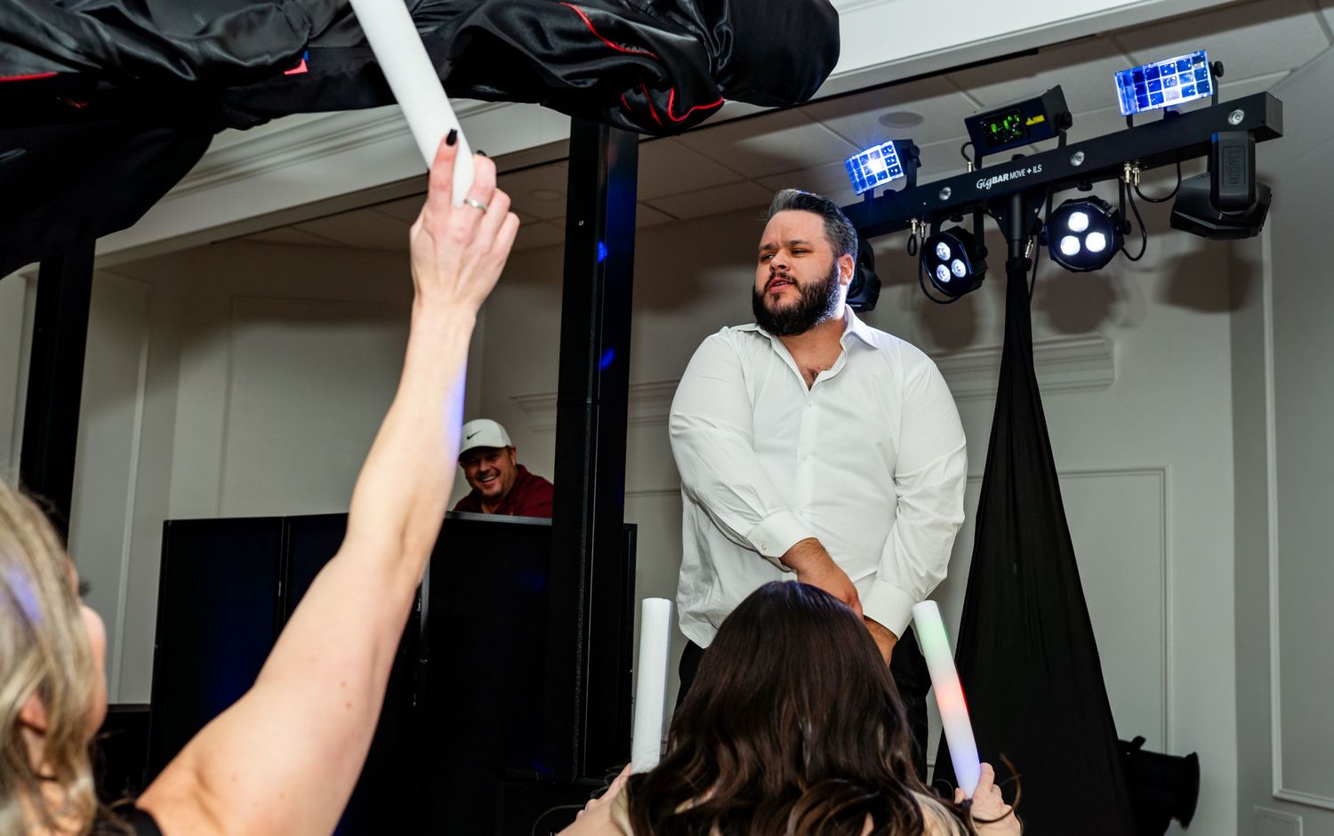 Professional photo shoot in a studio with lighting equipment and someone holding a white reflector overhead.