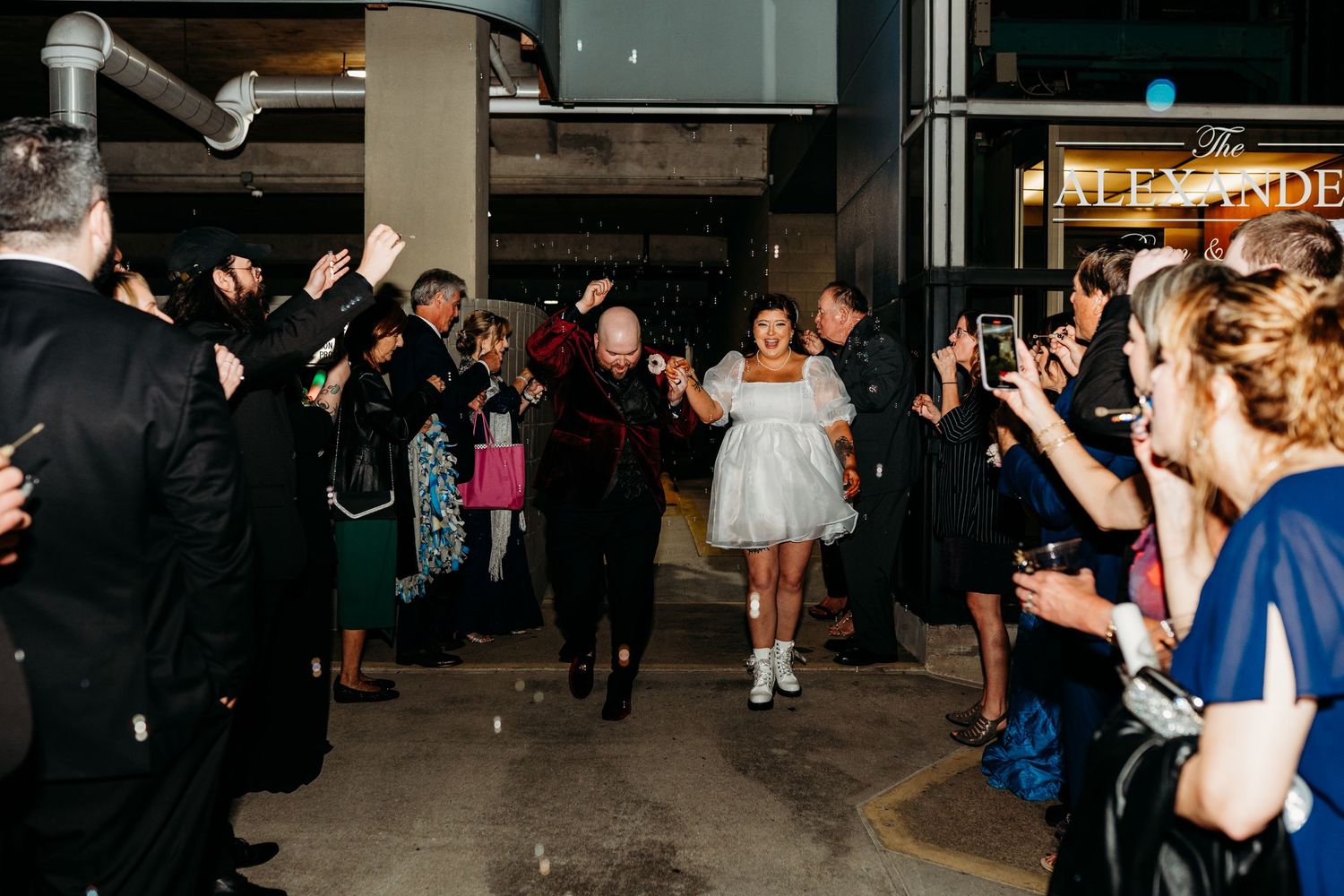 Guests with sparklers create a magical wedding exit line as someone in a white dress dances down the path.