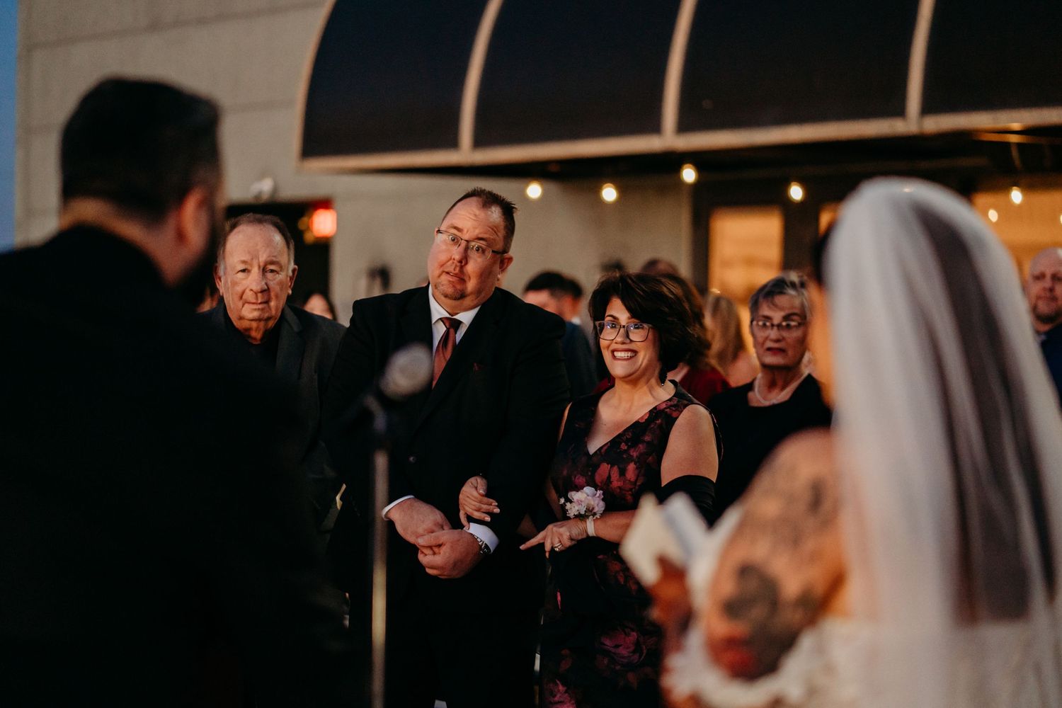 Wedding ceremony attendees react with joyful expressions as they observe a moment during an indoor evening service.
