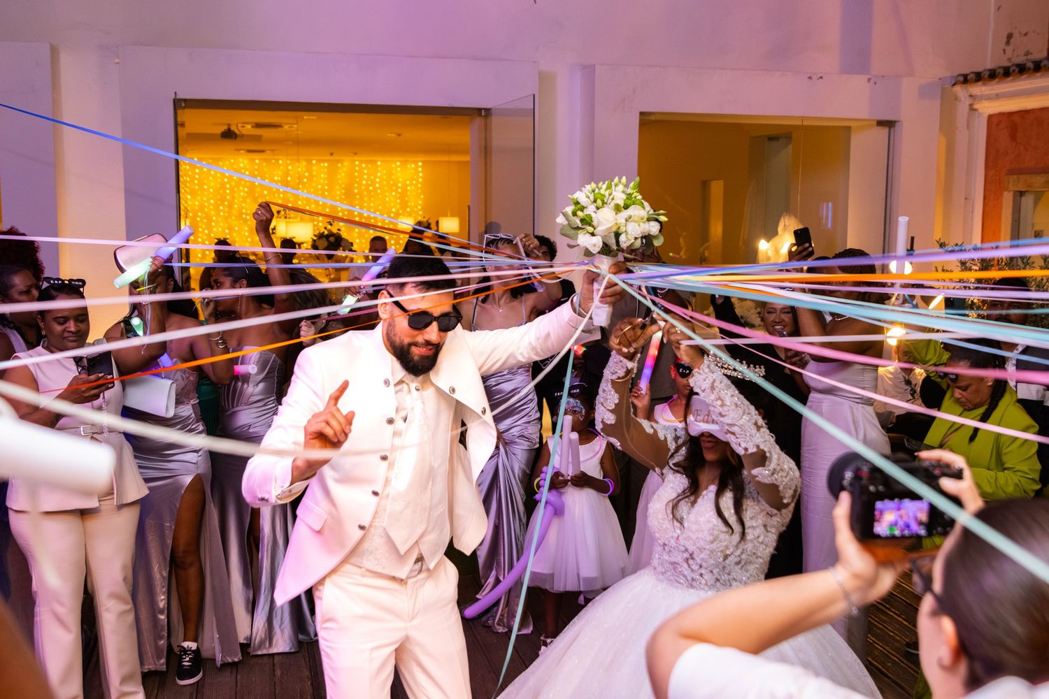 Wedding reception celebration with glowing lights and dancing guests.