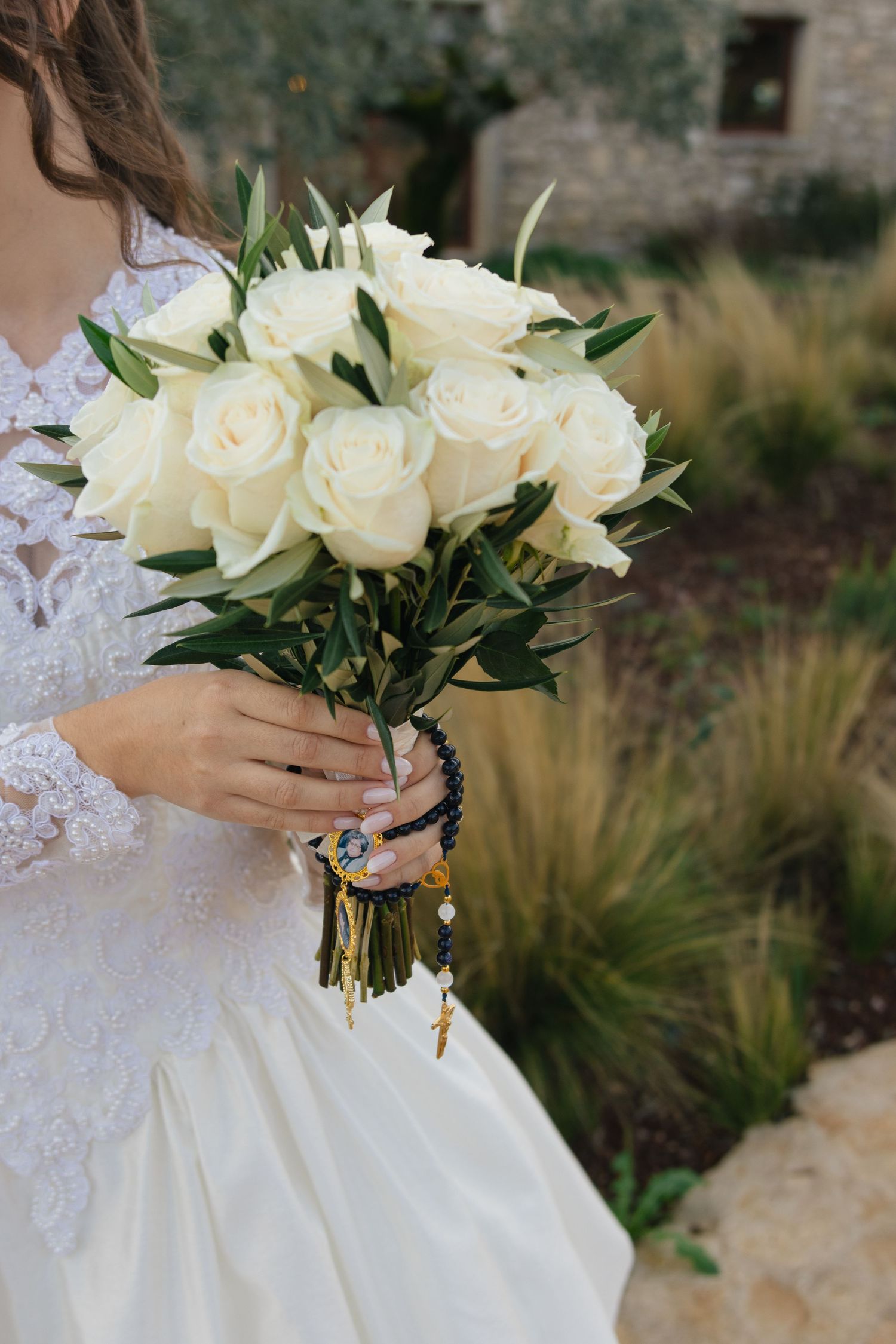 Close-up detail shots of a white rose wedding bouquet with green foliage held against a lace wedding dress.