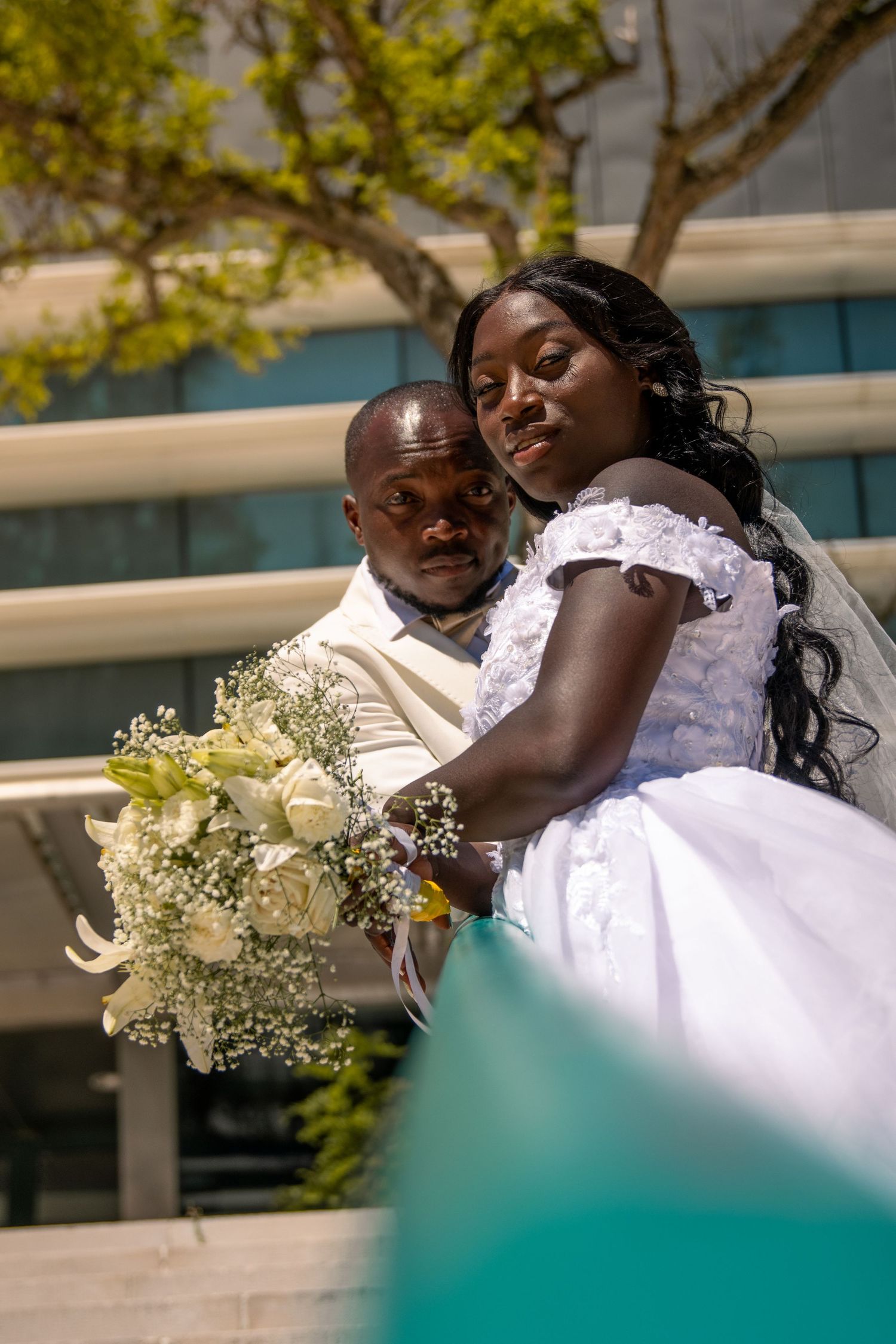 Newlyweds share a tender moment on an outdoor terrace with white flowers.