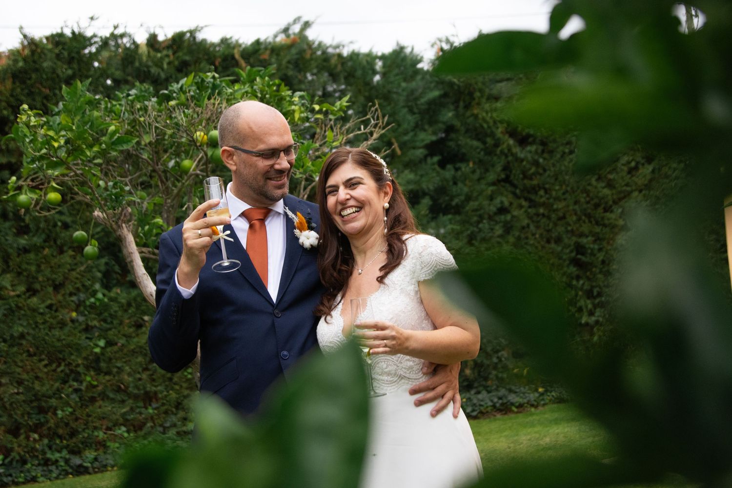A romantic wedding moment captured through green foliage in an outdoor garden setting.