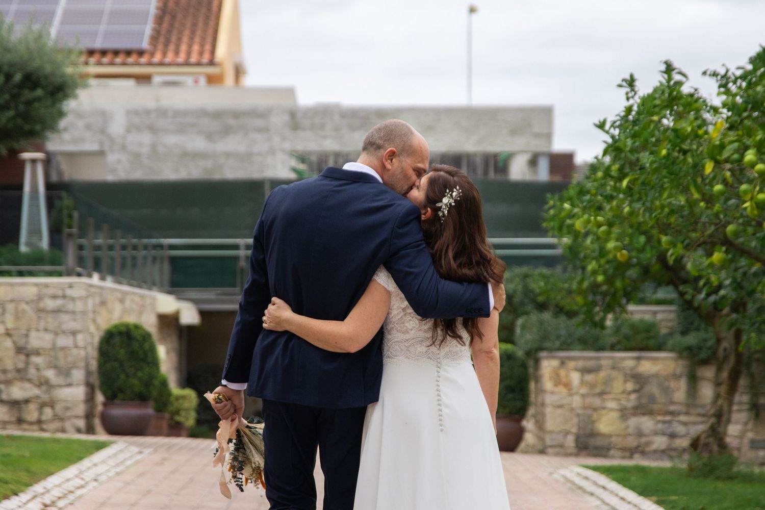 A couple shares an intimate dance moment on their wedding day in a garden setting.