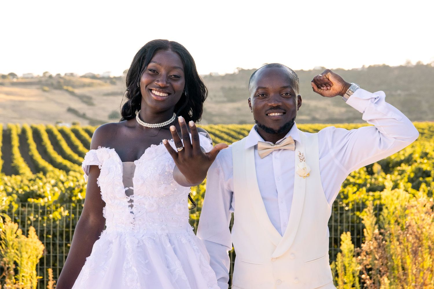 A couple shares a romantic moment while posing in a scenic vineyard setting.