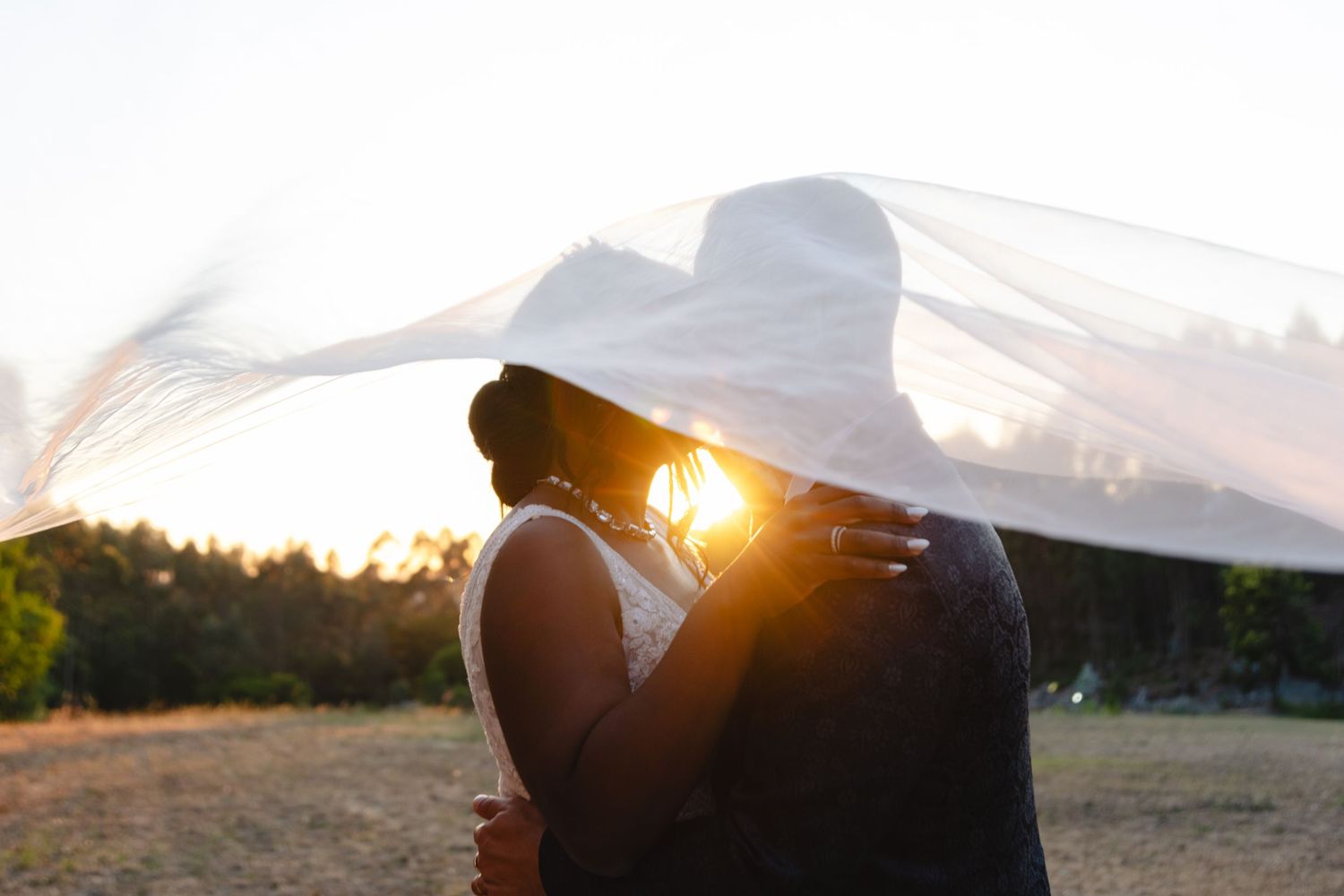 Silhouetted wedding couple embracing during golden hour sunset.