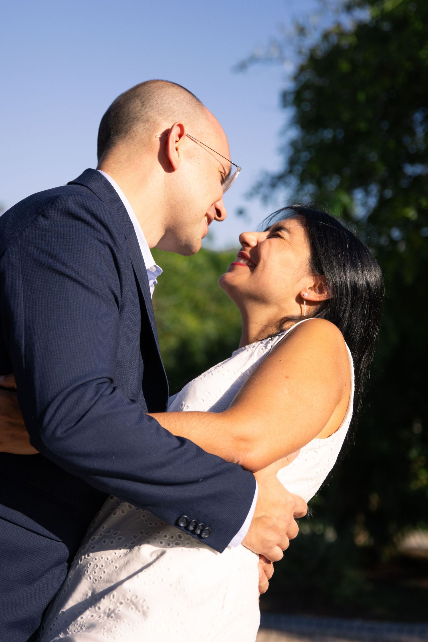 Romantic wedding couple sharing intimate kisses in an outdoor garden setting with natural lighting.