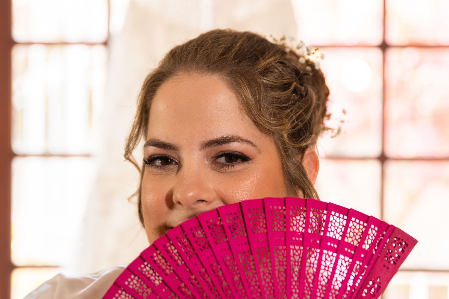 Wedding party members holding bright pink decorative fans.