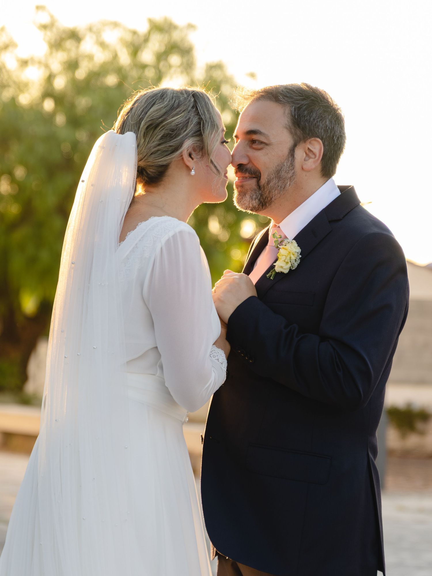 A tender moment between a couple in wedding attire during golden hour.