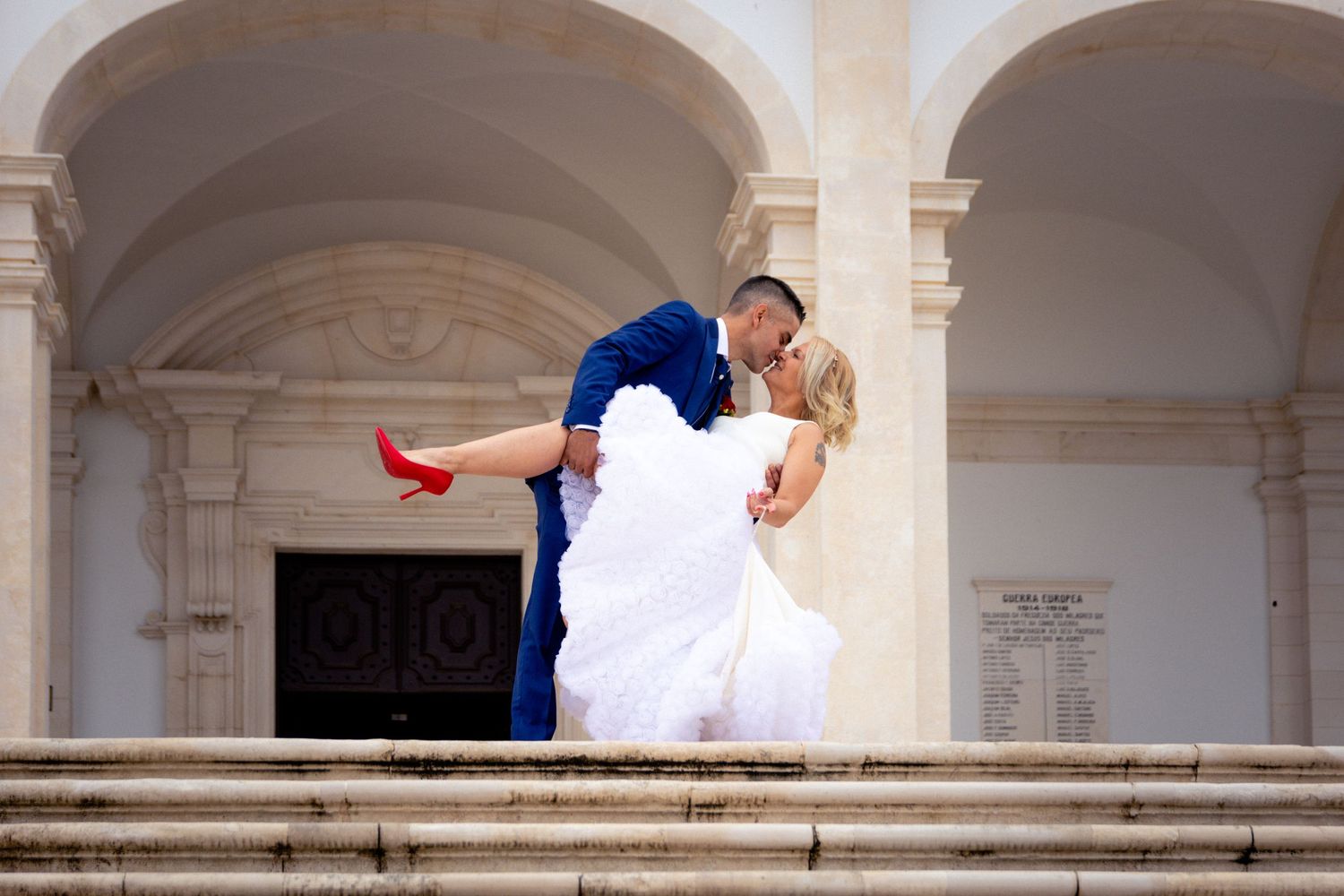 Wedding couple poses dramatically on classical architecture steps.