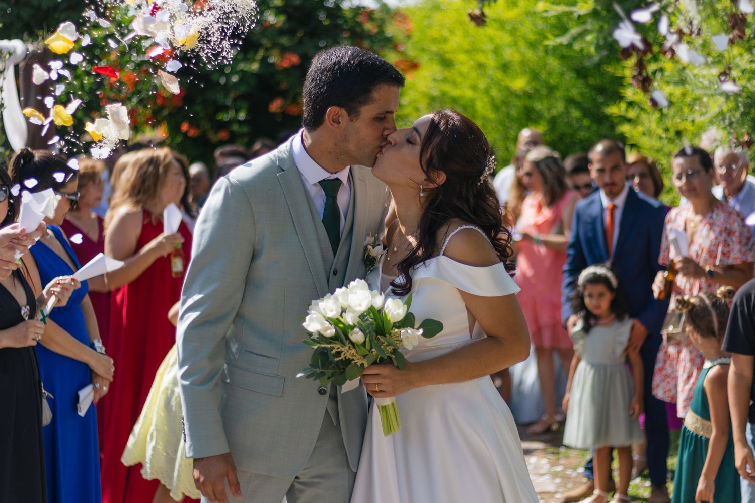 Wedding guests shower the newlyweds with confetti during an outdoor ceremony.