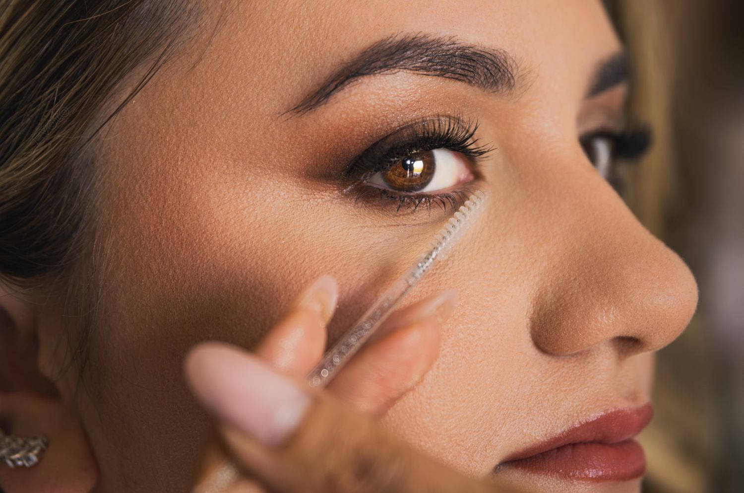 Close-up beauty shots showing glamorous bridal makeup application with dramatic eye makeup and nude lips.